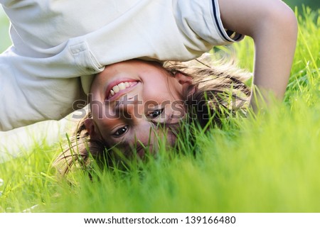 Portraits of happy kids playing upside down outdoors in summer park walking on hands