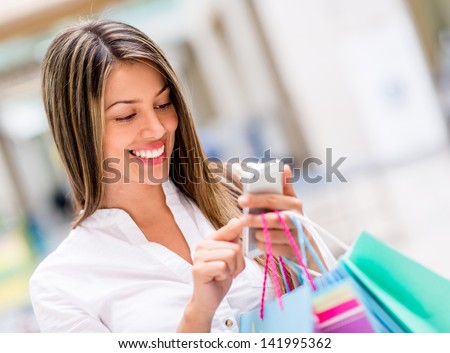 Happy woman using cell phone at a shopping center