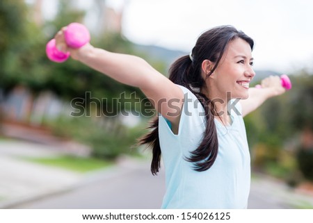 Excited woman training outdoors with arms up looking very happy 