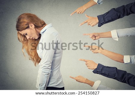 Concept of accusation guilty businesswoman person. Side profile sad upset woman looking down many fingers pointing at her isolated grey office background. Human face expression emotion feeling
