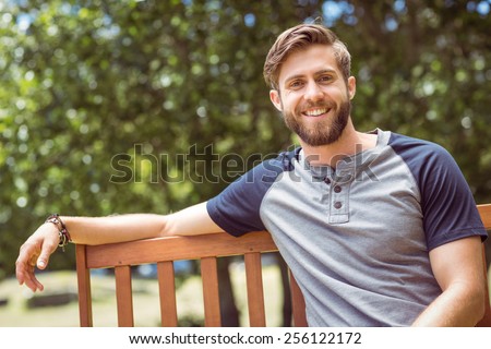 Joven relajándose en el banco del parque en un día de verano