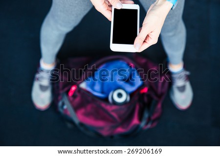 Closeup image of a sports woman holding smartphone