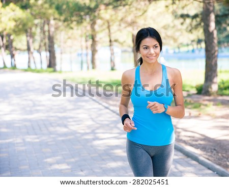Smiling sporty woman running outdoors in park