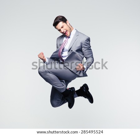 Funny cheerful businessman jumping in air over gray background