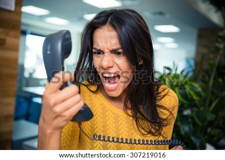Angry businesswoman shouting on phone in office