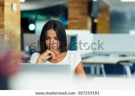 Portrait of a serious businesswoman using laptop in office 