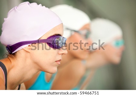 Female swimmers wearing hat and goggles ready to compete