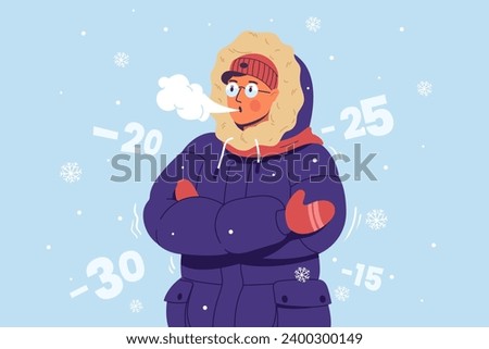 A young man in warm clothes, a hat and gloves is freezing and shivering from the cold. Freezing guy blows steam from his mouth. Cold weather.
