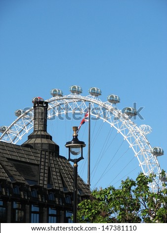 LONDON, UK - JUNE 26: View of black roof, street lamp, britain flag and famous London Eye on June 26, 2011 in London, UK. The London Eye is the the most popular tourist attraction in the UK.