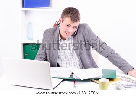 Young and handsome businessman in his office working and making conversation on his mobile phone