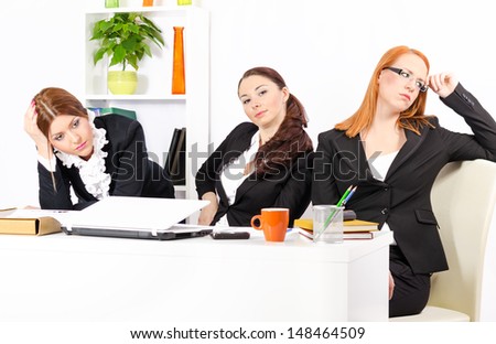 Three young and pretty businesswomen in their office trying to solve the problem together
