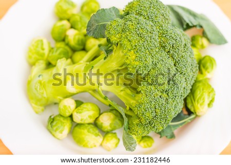 Raw broccoli and brussels sprout in a white plate on the kitchen table washed and ready for cooking