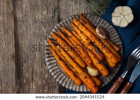 Healthy Homemade Roasted Carrots Ready to Eat. Glazed carrot with herbs and garlic. Fried carrot on wooden background. Sauteed vegetables. Comfort food