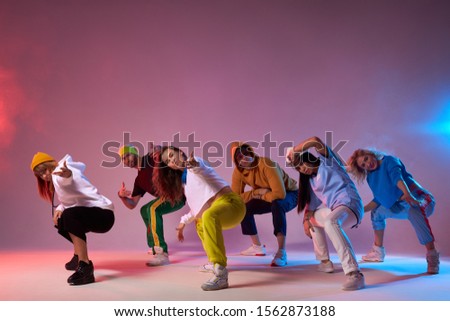 Famous group finish dancing , sitting on squats, looking at audience, making come alone gesture, expressing cheerfulness, dressed in sportswear, hip hop, street dance , break dance concept Foto stock © 