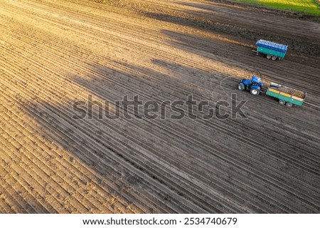 Similar – Image, Stock Photo Potato plantation and tractor farmer cultivating rows. Agroindustry and agribusiness. Cultivation of a young potato field. Loosening of the soil between the rows of bushes. Blurry