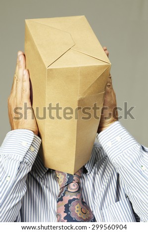 Embarrassed businessman wears a brown paper bag over his head