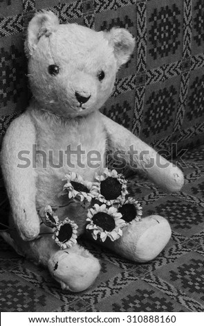 Vintage teddy bear with flowers on lap