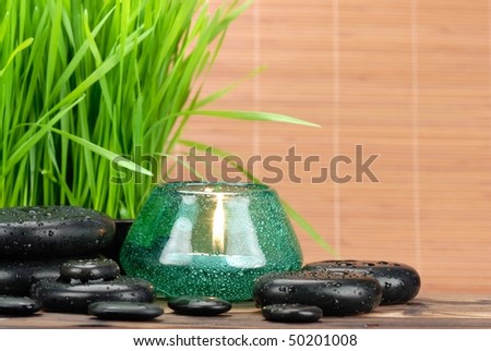 Spa still life with fresh green grass,zen stones and burning candle.