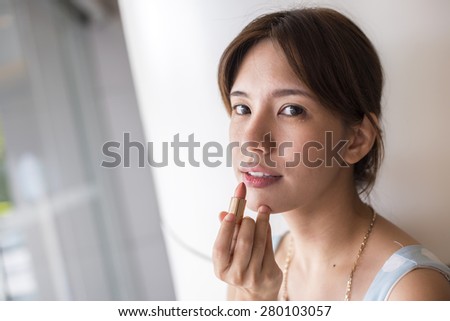 Beauty woman putting lipstick on the face. Portrail of Asia