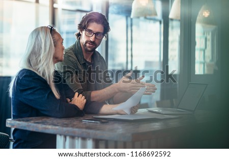 Young man explaining his idea of business to mature female colleague at work. Business people having a meeting for project discussion. Stock foto © 