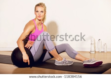Fitness instructor at the gym sitting on the floor with a pilates ball