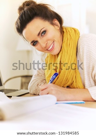 Closeup of a cheerful woman writing something in her journal