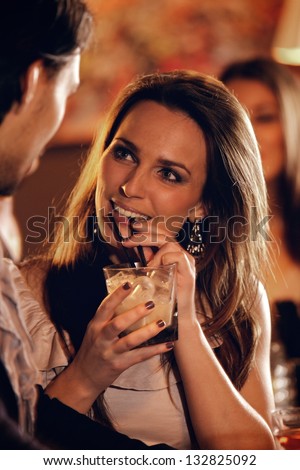 Closeup of a beautiful woman at the bar talking with a guy