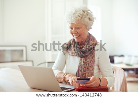 Happy old lady doing some shopping online using her laptop