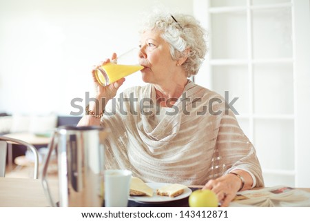 Elderly woman drinking a glass of orange juice