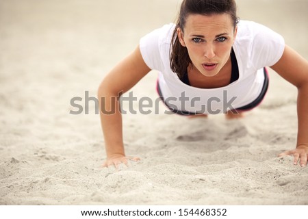 Push-ups fitness woman doing pushups outside on beach. Fit female sport model girl training crossfit outdoors. Caucasian athlete in her 20s.