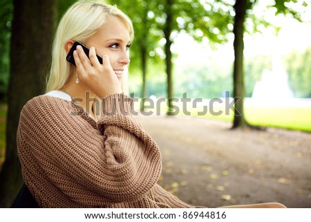 Sexy sensual blonde female model In animated conversation on her mobile phone in the park.