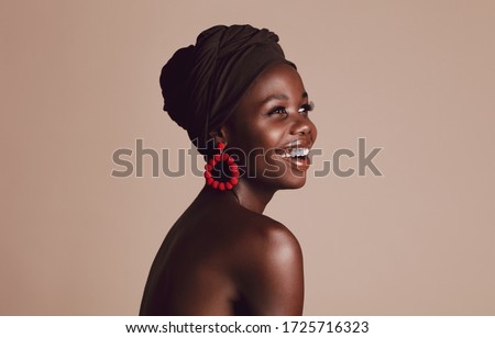Close up of smiling african woman on beige background. Beautiful female model with a cloth wrapped on head looking away and smiling.