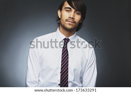Portrait of handsome young male business executive staring at camera against grey background. Asian young business. Male model wearing shirt and necktie.