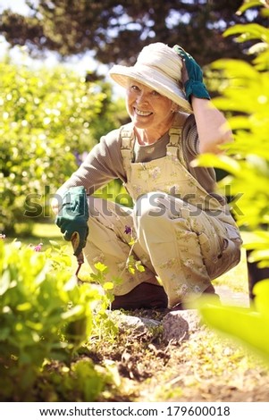 Happy older woman gardening in backyard looking at camera smiling