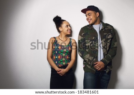 Happy young man and woman looking at each other smiling. Young couple in love against grey background.