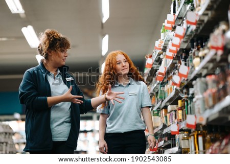 Grocery store manager training new female worker. Grocery store manager explaining work to a new saleswoman.