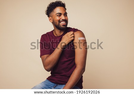 Man smiling after receiving vaccination. Man showing his arm after receiving a vaccine.