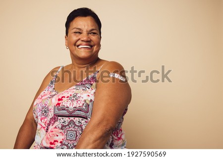 Portrait of a mature female smiling after getting a vaccine. Woman looking away and smiling after receiving vaccination.