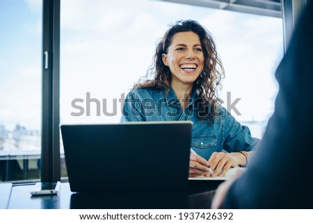 Businesswoman taking interview of a job applicant in office boardroom. Smiling recruiter asking questions to a male candidate during job interview.
