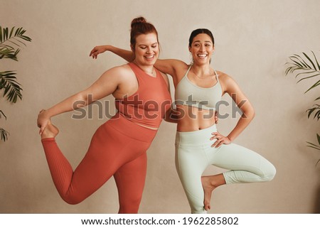 Women sportswear standing together on one leg at fitness studio. Females exercising at health club.