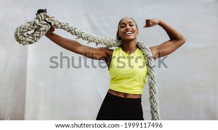 Strong African woman showing her muscular biceps with a battle rope. Fitness woman flexing arm muscles after cross training workout. Stock foto © 
