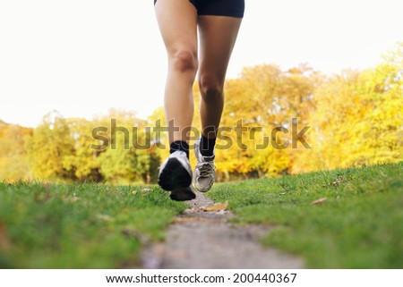 Close-up of feet of a runner running in park. Woman training for fitness. Female legs jogging in park - Outdoors