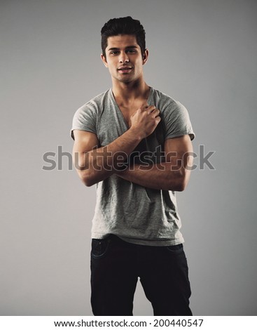 Portrait of handsome young man posing confidently. Hispanic male fashion model against grey background.