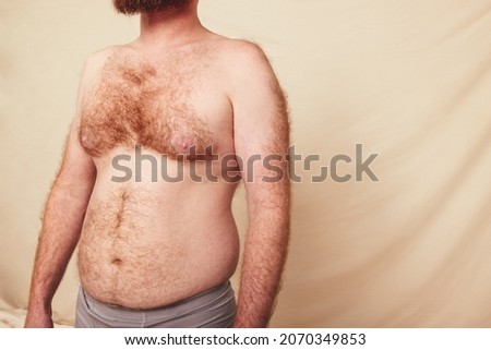 Hairy man with a pot belly embracing his natural body. Unrecognizable man wearing grey underwear in a studio. Body positive and self-confident man standing alone against a studio background. Photo stock © 