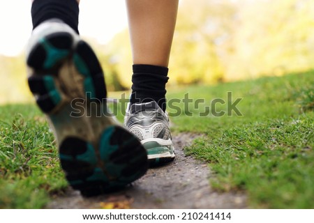 Feet of a runner in park. Woman walking in the park, close up of feet. Fitness and exercising training.