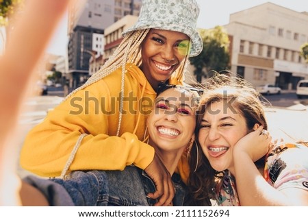 Trio of friends taking a selfie together. Group of multiethnic female friends having fun together outdoors. Cheerful generation z friends capturing their happy moments in the city. Stok fotoğraf © 