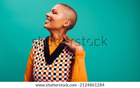 Confident short-haired woman smiling in a studio. Happy young woman standing with her eyes closed against a turquoise background. Fashionable young woman wearing a septum ring. Foto stock © 