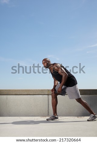 Full length image of fit and strong young male model ready for his run. Muscular male athlete outdoors.