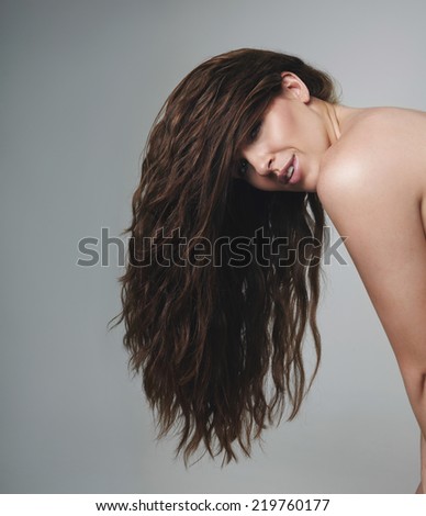 Female model with beautiful long hair looking at camera. Brunette woman on grey background