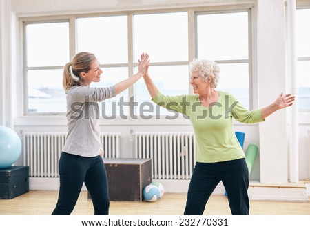 Senior woman giving high five to her physical therapist at rehab. Happy elderly woman celebrating fitness success with her instructor at gym.